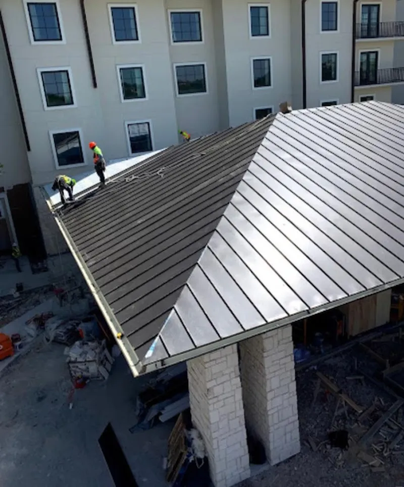 Crew installing standing seam metal roof panels on a commercial project in Gardiner